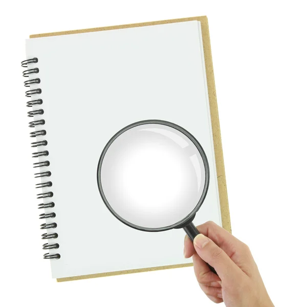 Hand holding magnifying glass over blank notebook — Stock Photo, Image