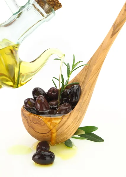 Aceite de oliva vertido en una cuchara de madera llena de aceitunas —  Fotos de Stock