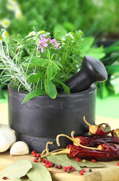 Černý kámen moždíř s čerstvými bylinkami — Stock fotografie