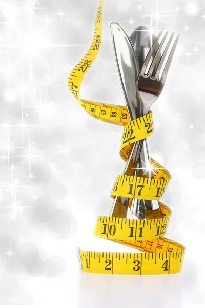 Christmas diet concept represented by a cutlery set with measuring tape — Stock Photo, Image