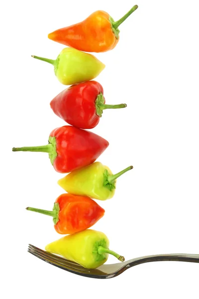 Colorful hot mini chili peppers balance on fork, isolated on white — Stock Photo, Image