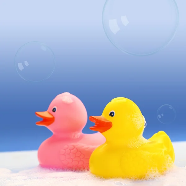 Желтые и розовые резиновые утки в пене для ванны — стоковое фото