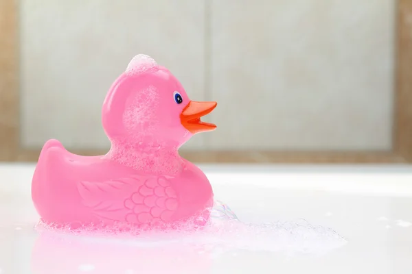Pato de borracha rosa em espuma de banho — Fotografia de Stock