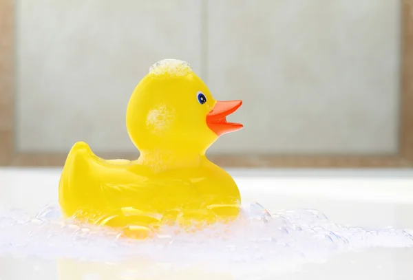 Pato de borracha amarelo na espuma do banho — Fotografia de Stock