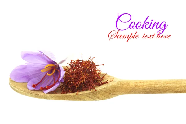Spezia di zafferano essiccata e fiore di zafferano su cucchiaio di legno — Foto Stock