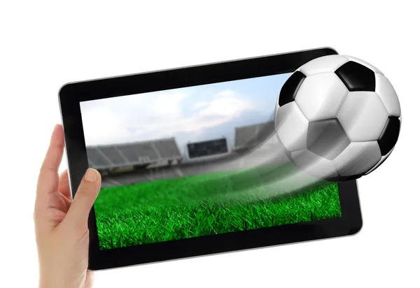 Tablet mão segurando com bola de futebol voando fora da tela — Fotografia de Stock