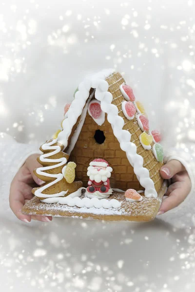 Mains féminines tenant maison festive en pain d'épice, avec neige — Photo
