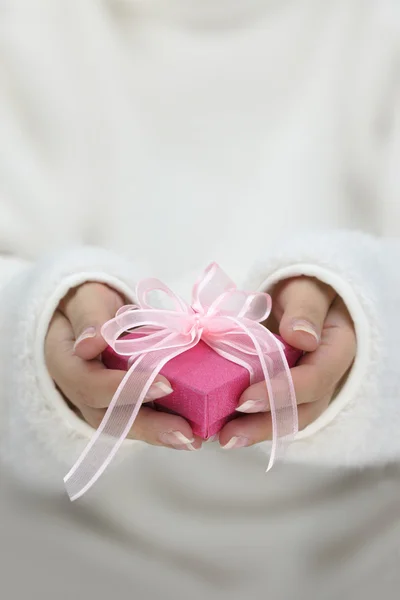 Manos con mangas largas blancas sosteniendo caja de regalo envuelta —  Fotos de Stock