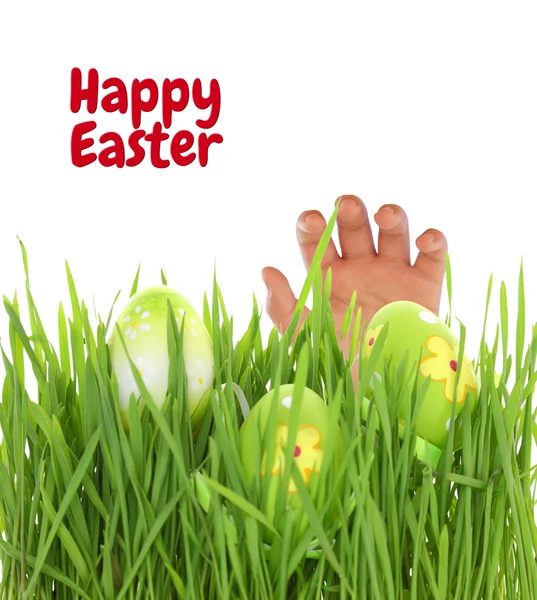 Hand reaching for Easter egg on green grass — Stock Photo, Image