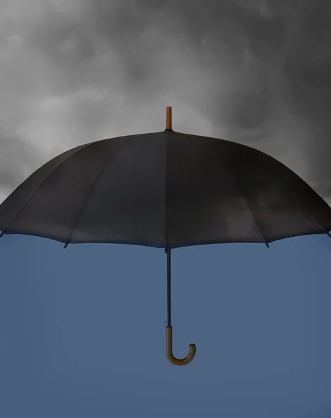 Guarda-chuva com nuvens pesadas acima e azul claro sob — Fotografia de Stock
