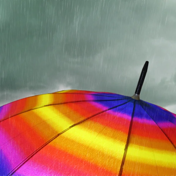 Top guarda-chuva colorido com chuva pesada e nuvens — Fotografia de Stock