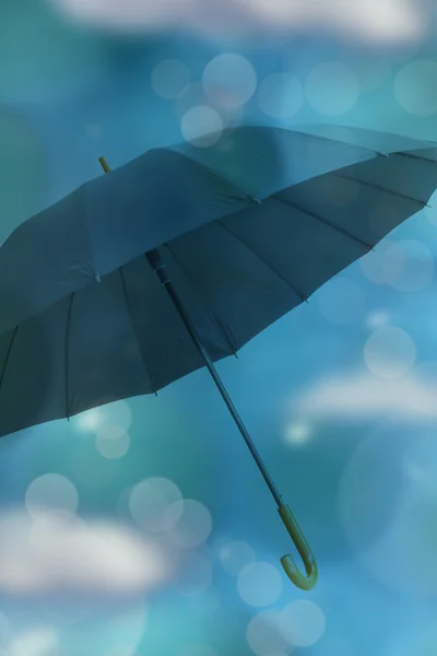 Guarda-chuva em fundo azul com bokeh e nuvens — Fotografia de Stock