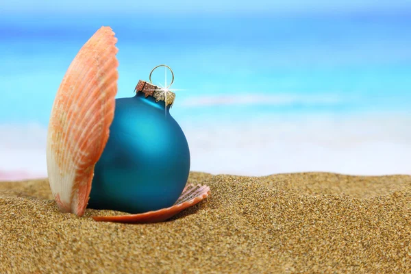 Hristmas ball in a sea shell on the beach — Stock Photo, Image