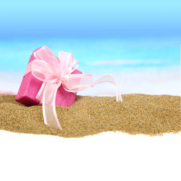 Gift box with ribbon on the sand — Stock Photo, Image