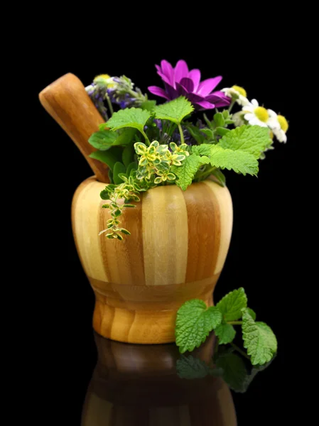 Mortar and pestle with fresh herbs on black background — Stock Photo, Image