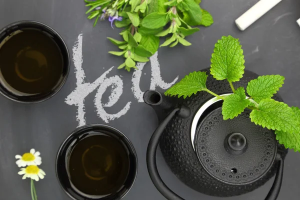 Theepot met kruiden en theekopjes op schoolbord top shot — Stockfoto