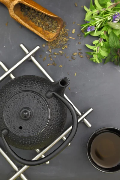 Tischplatte mit Teekanne getrocknet und frischen Kräutern und Teetasse — Stockfoto