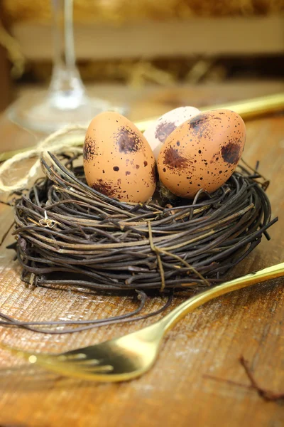 Huevos de Pascua en el nido y tenedor dorado sobre fondo de madera — Foto de Stock