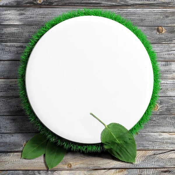 White frame with grass and leaves on wooden background — Stock Photo, Image