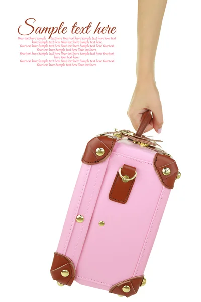 Kezében egy elszigetelt fehér rózsaszín utazási bőrönd — Stock Fotó