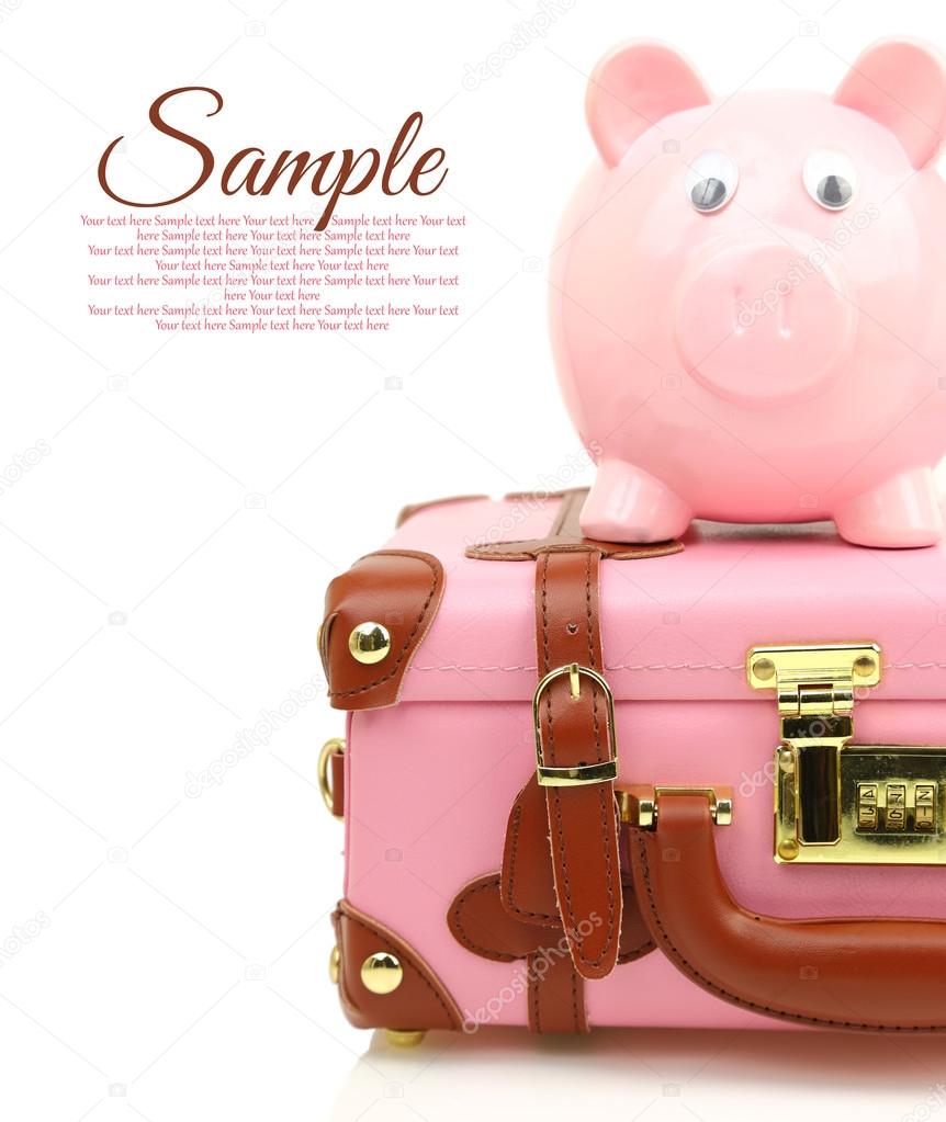 Pink suitcase with piggy bank and copy-space