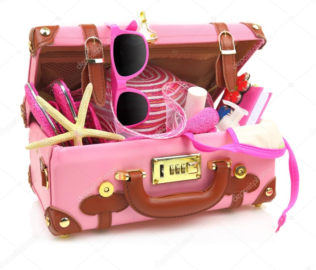Ready to travel pink suitcase with summer equipment isolated