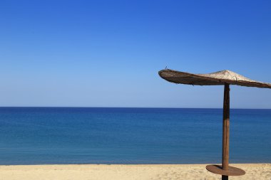 Sunny beach with wicker umbrella