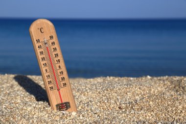 Thermometer on a beach shows high temperatures clipart