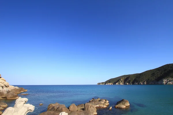 Mare con rocce costiere, acqua limpida e cielo azzurro — Foto Stock