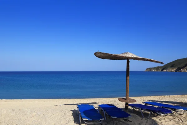 Spiaggia soleggiata con ombrellone e lettini in vimini — Foto Stock