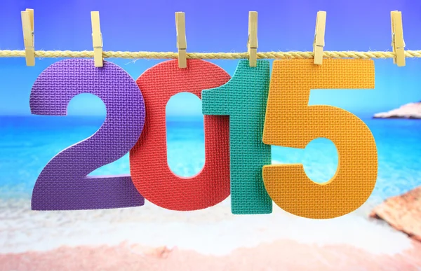 Colorful number 2015 year hanging on a rope in front of the sea Royalty Free Stock Photos