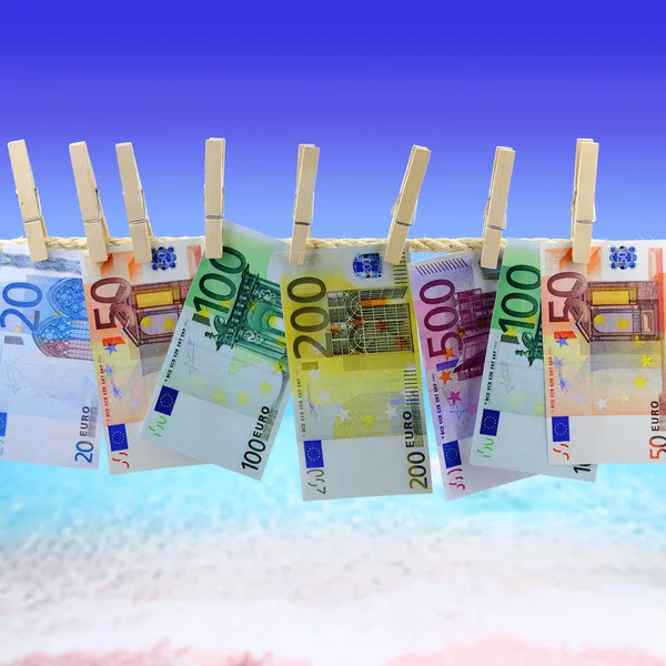 Bankbiljetten opknoping op waslijn tegenover het strand — Stockfoto