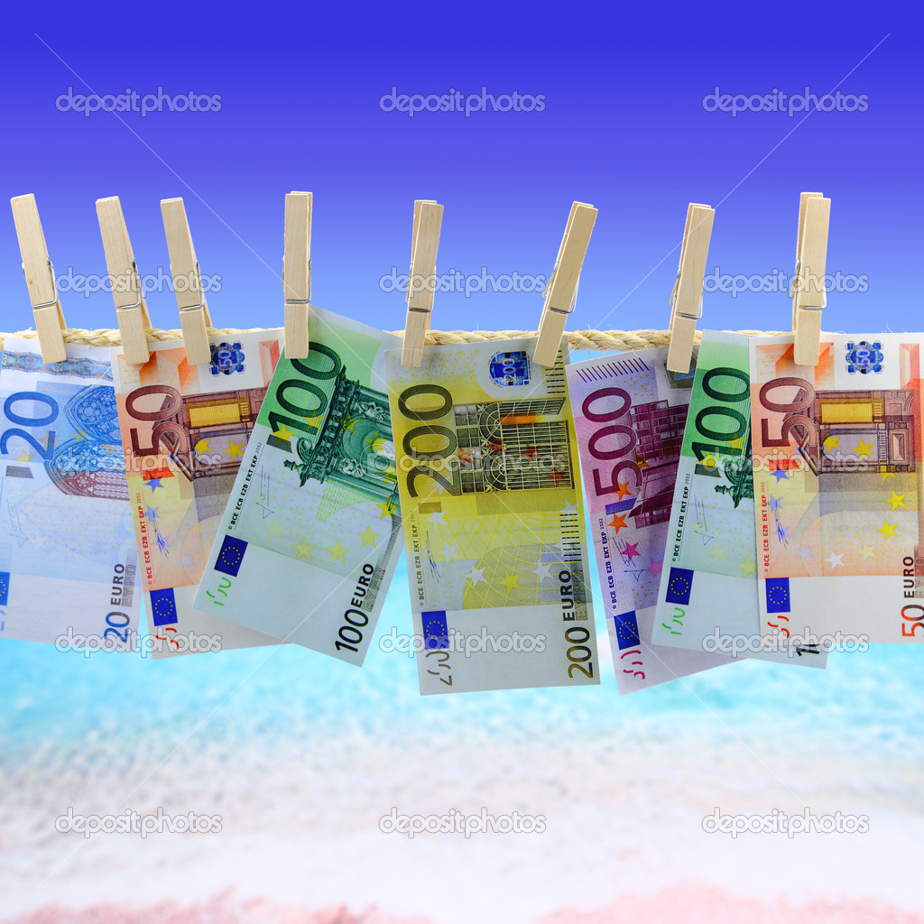 Banknotes hanging on clothesline in front of the beach