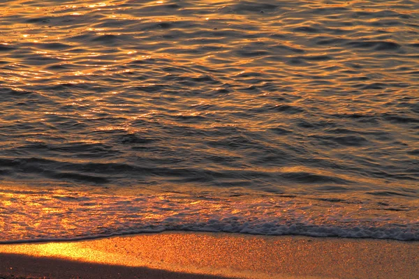 Goldene Meereswellen und Sand bei Sonnenuntergang, Nahaufnahme — Stockfoto