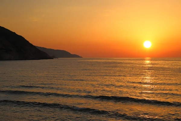 Sonnenuntergang am Strand mit weit entfernten Bergsilhouetten — Stockfoto