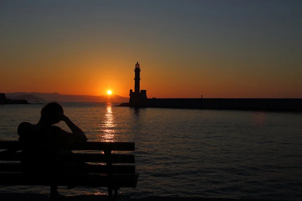 Deniz feneri Hanya Girit arkasında gün batımını izlemek kadın — Stok fotoğraf