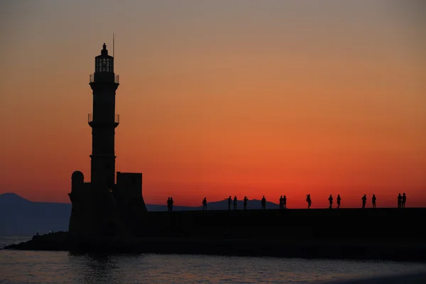 Deniz feneri ve insan siluetleri alacakaranlıkta Hanya Girit — Stok fotoğraf