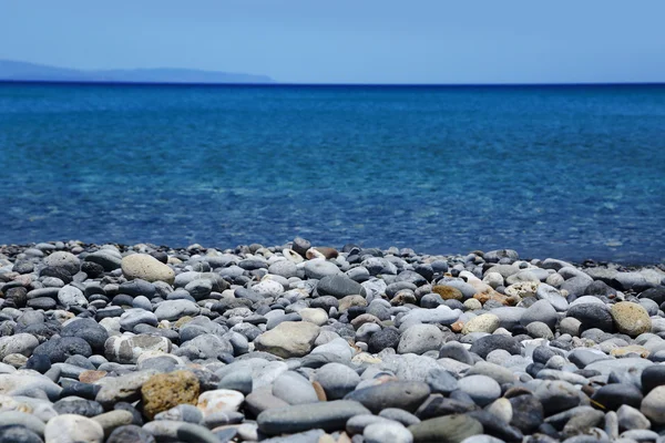 Strand mit Kieselsteinen und blauem Meersitia-Beton — Stockfoto