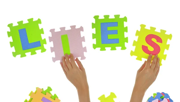 Hands forming word "Lies" with jigsaw puzzle pieces — Stock Photo, Image