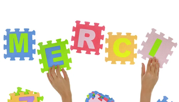 Hands forming word "Merci" with jigsaw puzzle pieces isolated — Stock Photo, Image