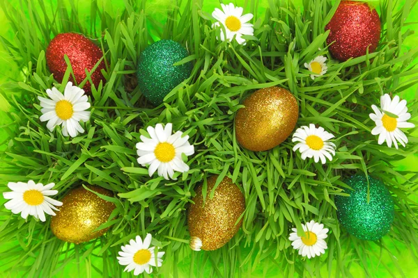 Pasen achtergrond met gras, bloemen en kleurrijke glitter eieren — Stockfoto