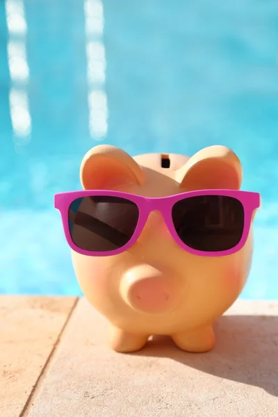 Tirelire d'été avec lunettes de soleil devant une piscine — Photo