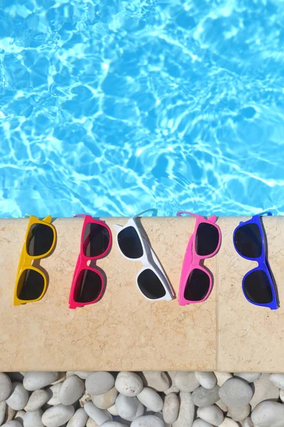 Óculos de sol coloridos na fila à beira da piscina — Fotografia de Stock