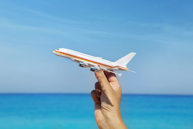 Uçak minyatür mavi ufuk arka plan ile tutan el 