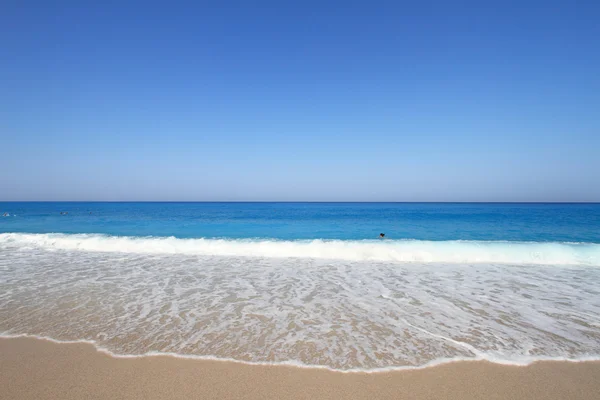 Песчаное побережье с голубым небом и водой — стоковое фото