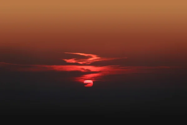 Dramatic red sunset with center sun and dark clouds — Stock Photo, Image