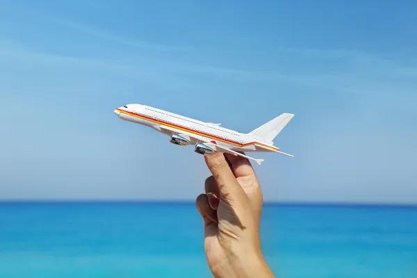 Ręka trzyma miniaturowe samolot z tle niebieski horyzont — Zdjęcie stockowe