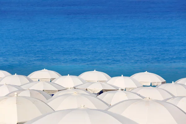 Spitzen von weißen Sonnenschirmen und Meer kathisma lefkada Griechenland — Stockfoto