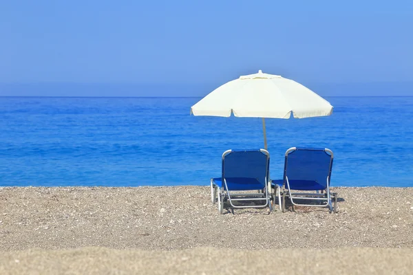 Zandstrand met parasol en twee ligbedden, gialos lefkada — Stockfoto