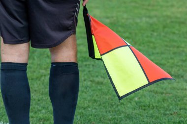Elinde bayrakla futbol hakemi asistanı. Bulanık yeşil alan arkaplanı, kapat